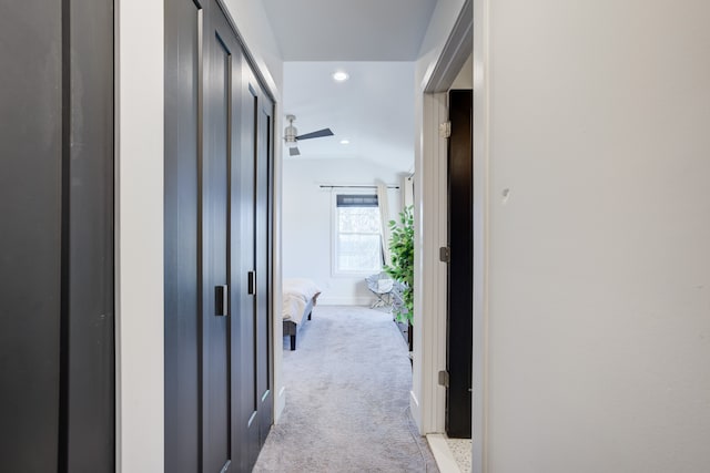 hallway with light carpet and vaulted ceiling