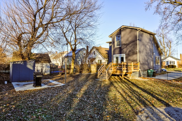 rear view of property with a storage unit and a wooden deck