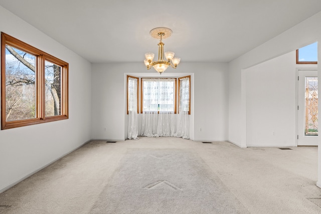 carpeted spare room with a chandelier