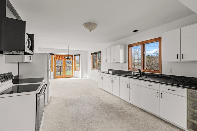 kitchen with light carpet, sink, electric stove, white cabinets, and hanging light fixtures