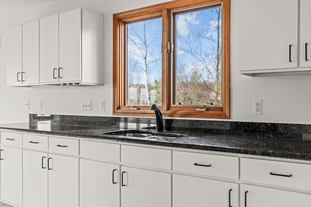 kitchen with plenty of natural light, white cabinetry, sink, and dark stone counters