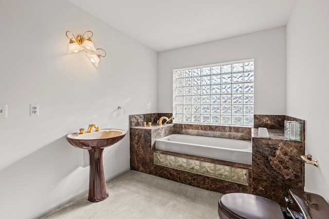 bathroom featuring tiled bath and toilet