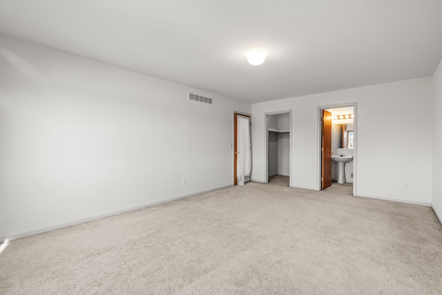 unfurnished bedroom featuring sink, light carpet, and ensuite bath