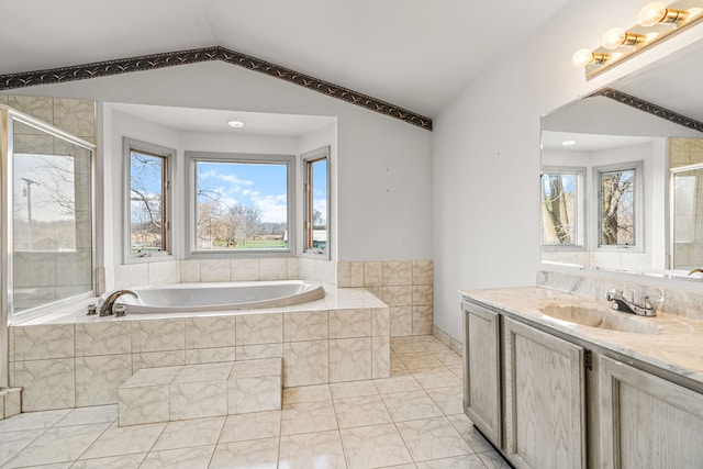 bathroom featuring tiled tub, vanity, and lofted ceiling