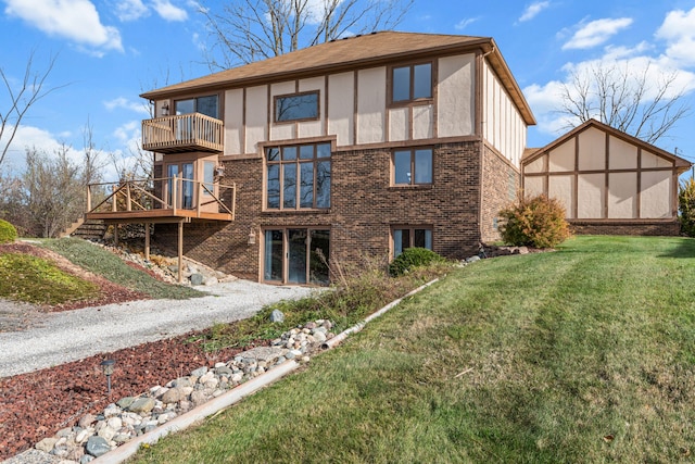 rear view of property featuring a balcony, a yard, and a wooden deck