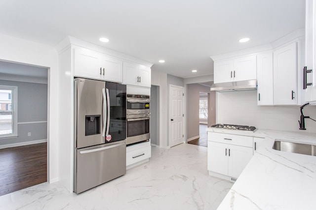 kitchen with sink, appliances with stainless steel finishes, tasteful backsplash, light stone countertops, and white cabinets