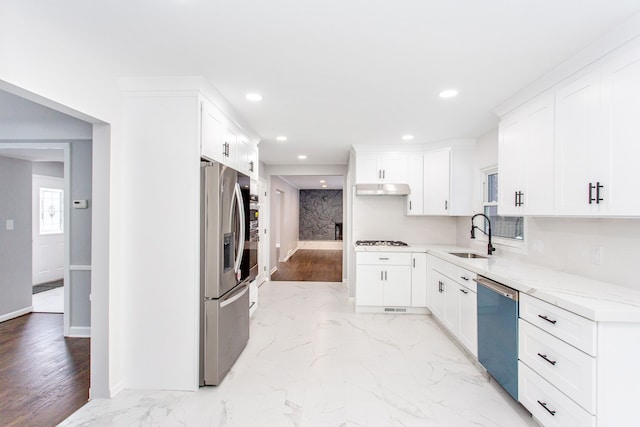 kitchen featuring stainless steel appliances, white cabinetry, light stone countertops, and sink