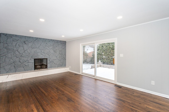 unfurnished living room with ornamental molding, a stone fireplace, and hardwood / wood-style floors