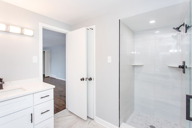 bathroom with a tile shower and vanity