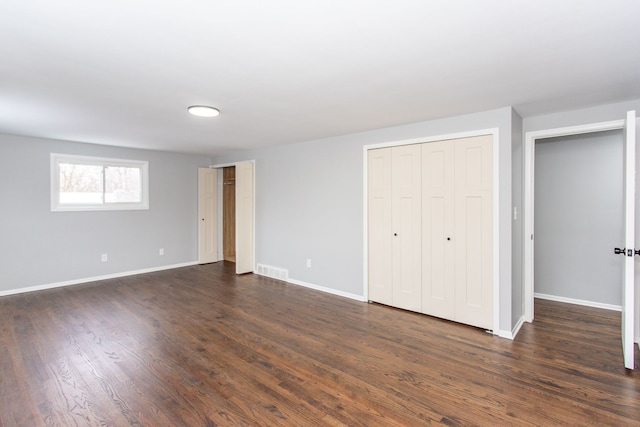 unfurnished bedroom with multiple closets and dark hardwood / wood-style floors