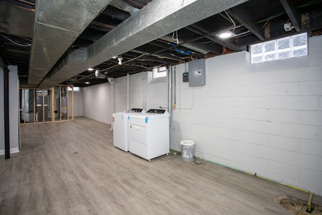 basement featuring wood-type flooring, washing machine and clothes dryer, and electric panel