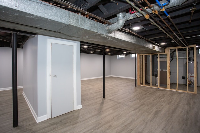 basement with heating unit, hardwood / wood-style floors, and water heater