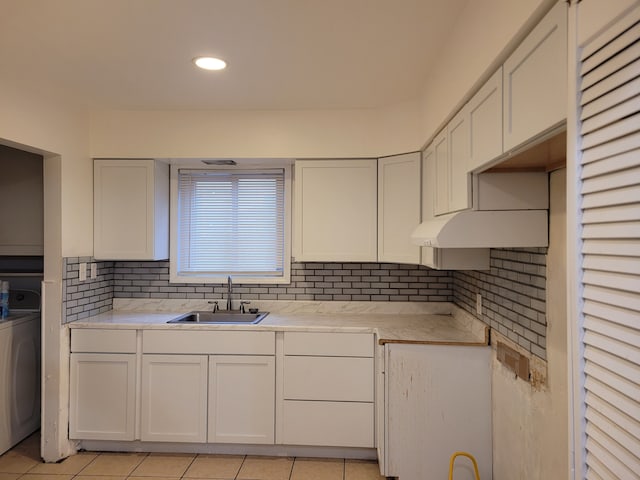 kitchen featuring washer / clothes dryer, white cabinetry, sink, and light tile patterned flooring