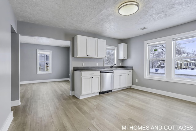 kitchen featuring white cabinetry, sink, stainless steel dishwasher, a textured ceiling, and light wood-type flooring