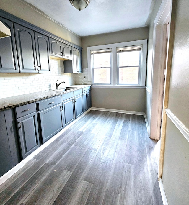 kitchen with backsplash, light stone countertops, sink, and dark wood-type flooring