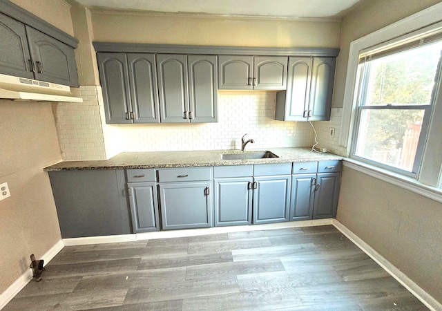 kitchen with backsplash, sink, hardwood / wood-style flooring, gray cabinets, and light stone counters