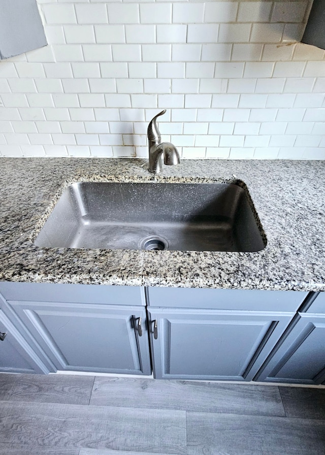 interior details featuring sink, hardwood / wood-style floors, and stone countertops