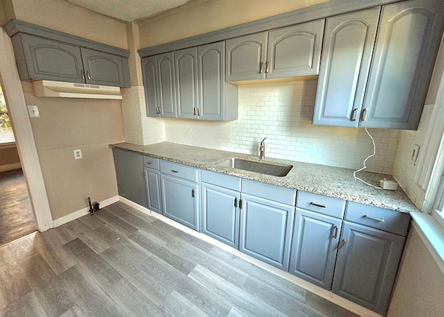 kitchen featuring gray cabinetry, dark wood-type flooring, sink, tasteful backsplash, and light stone counters