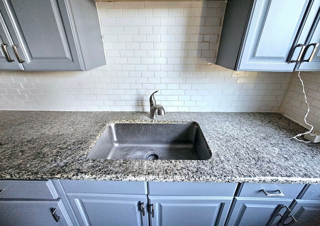 kitchen featuring dark stone countertops, decorative backsplash, sink, and gray cabinets