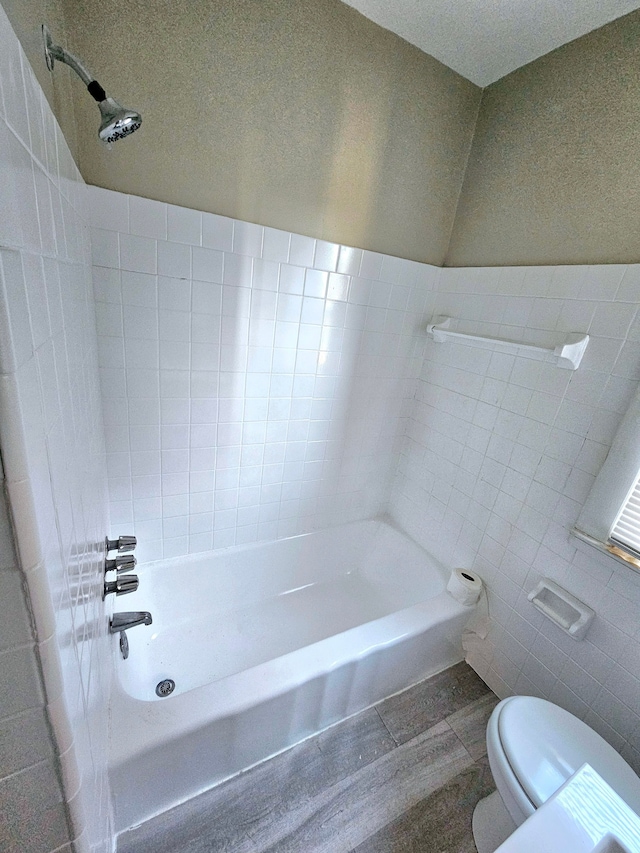 bathroom featuring toilet, tile walls, and tub / shower combination