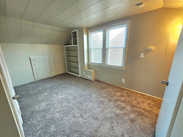 bonus room featuring carpet flooring, wood walls, and lofted ceiling