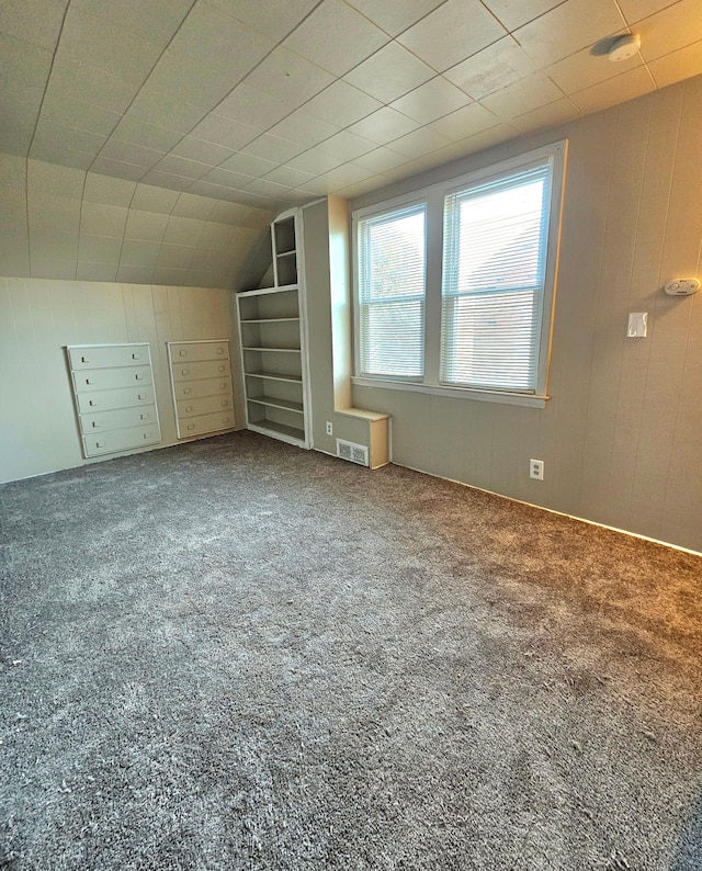 bonus room with carpet and wooden walls