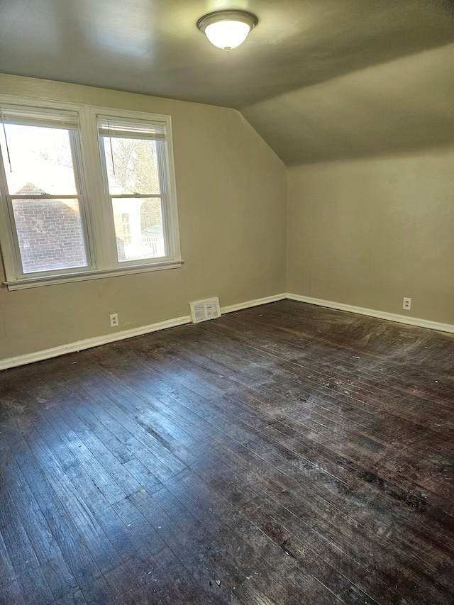 additional living space featuring dark wood-type flooring and vaulted ceiling