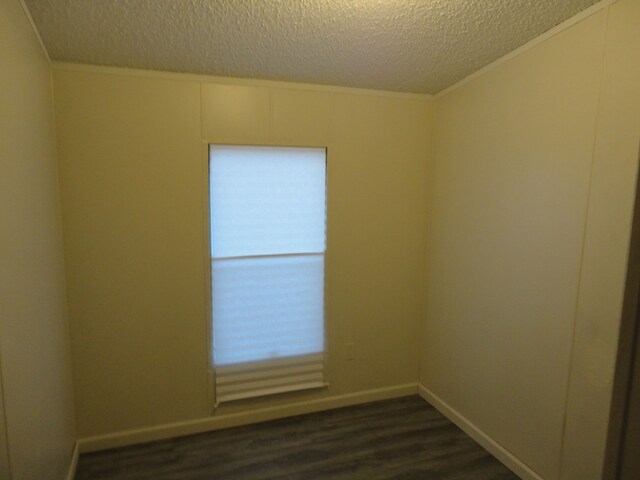 unfurnished room featuring a textured ceiling, crown molding, and dark wood-type flooring