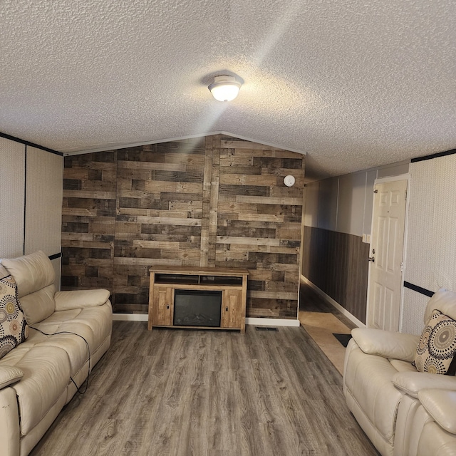 living room with hardwood / wood-style floors, a fireplace, a textured ceiling, and vaulted ceiling