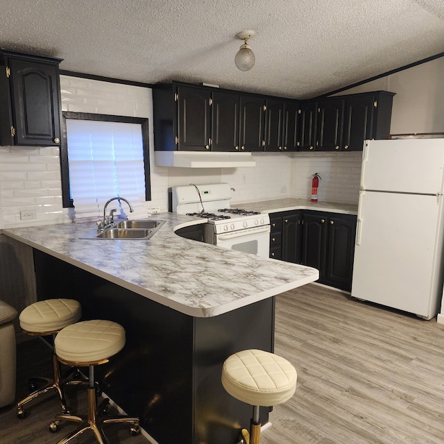 kitchen featuring sink, a breakfast bar area, white appliances, and kitchen peninsula