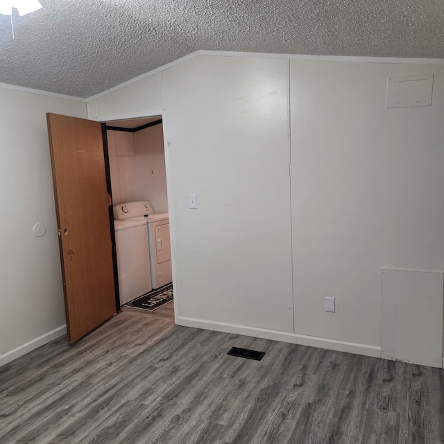 spare room featuring lofted ceiling, a textured ceiling, washer and clothes dryer, and wood-type flooring