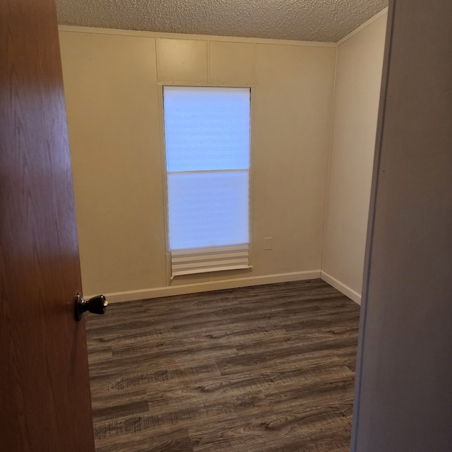 spare room featuring dark wood-type flooring and a textured ceiling