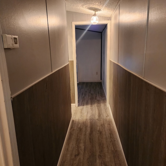 corridor with hardwood / wood-style flooring, a textured ceiling, and wood walls