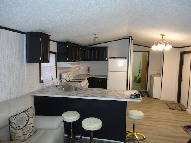 kitchen with a breakfast bar, washer / dryer, kitchen peninsula, pendant lighting, and white appliances