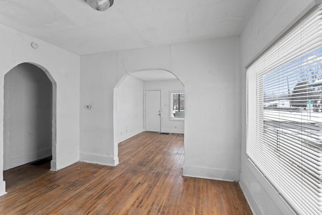 empty room featuring dark wood-type flooring and a healthy amount of sunlight