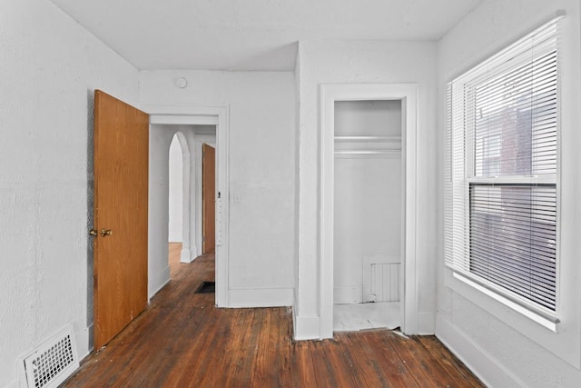 unfurnished bedroom with dark hardwood / wood-style flooring and a closet