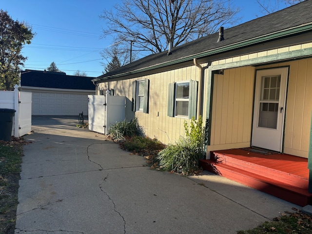 view of side of home with a wooden deck, a garage, and an outbuilding