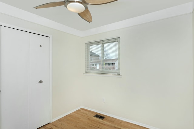 unfurnished bedroom featuring hardwood / wood-style floors, ceiling fan, and a closet