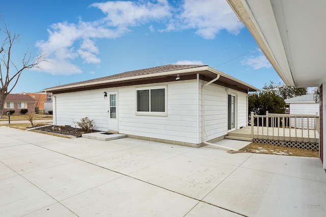 rear view of property with a wooden deck and a patio area