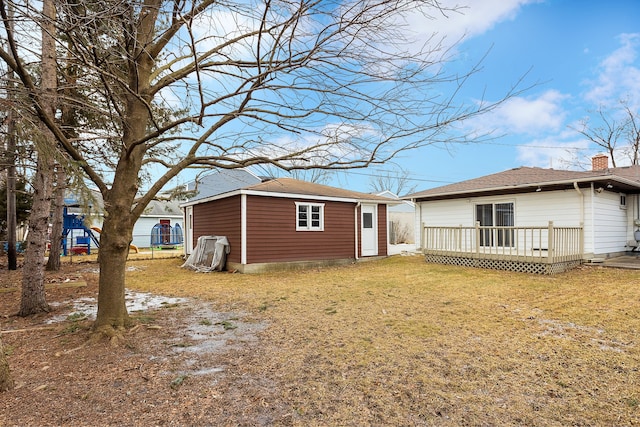 rear view of house featuring a wooden deck, an outdoor structure, and a yard