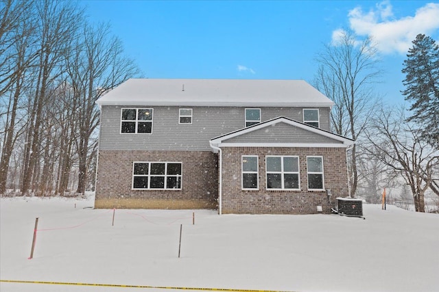 snow covered back of property featuring central AC