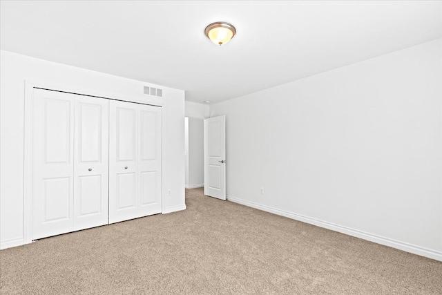 unfurnished bedroom featuring light colored carpet and a closet