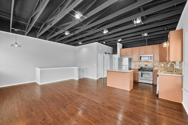 kitchen with sink, decorative backsplash, hanging light fixtures, a kitchen island, and appliances with stainless steel finishes