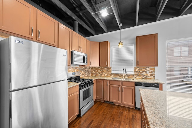 kitchen with sink, light stone counters, hanging light fixtures, dark hardwood / wood-style floors, and appliances with stainless steel finishes