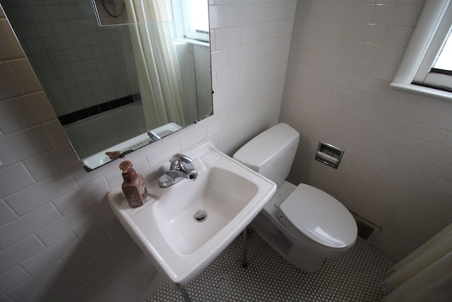 full bathroom featuring toilet, tile walls, tile patterned floors, shower / tub combo, and sink