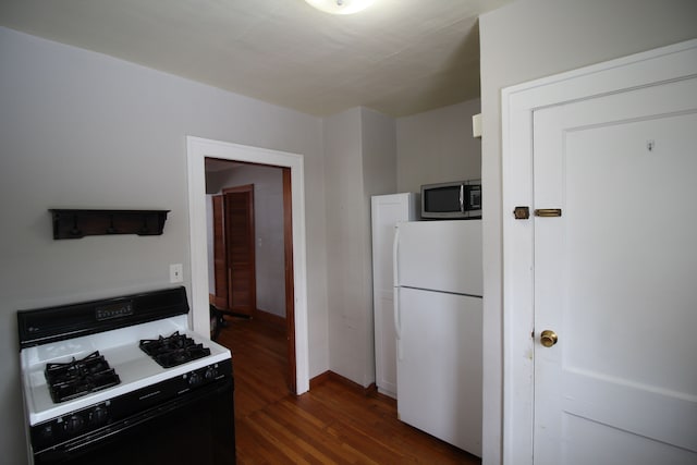 kitchen with dark hardwood / wood-style floors, white refrigerator, and black range with gas stovetop