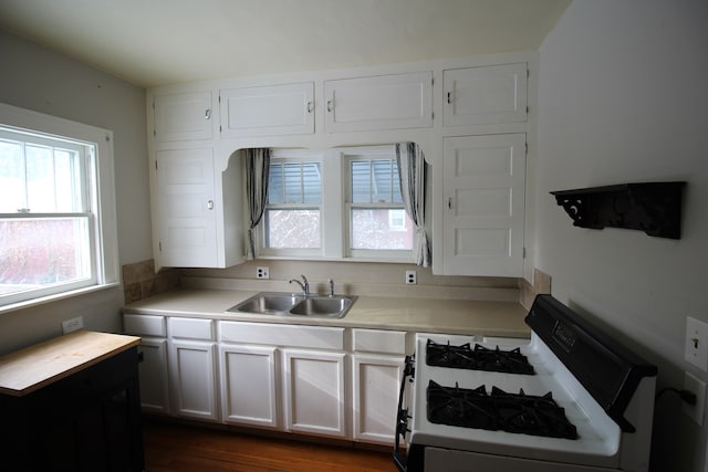 kitchen with a healthy amount of sunlight, gas range, white cabinets, and sink