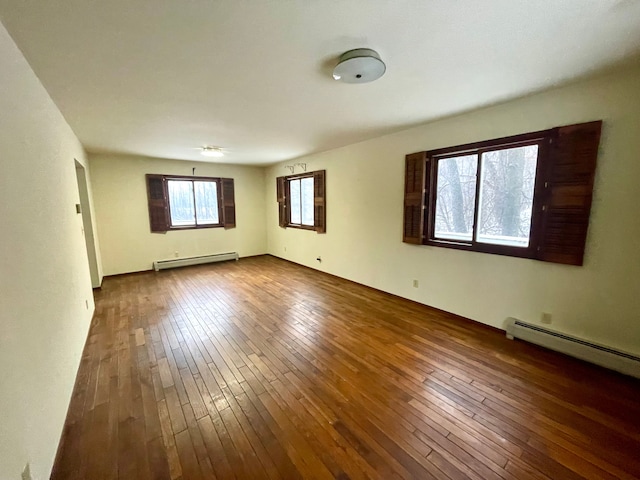 spare room featuring baseboard heating and dark wood-type flooring