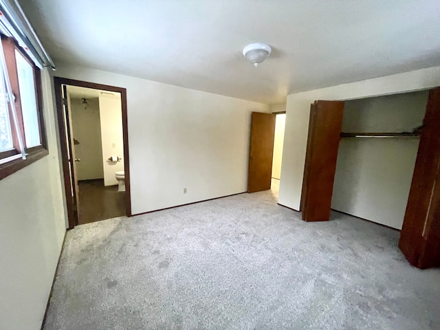 unfurnished bedroom featuring light carpet, ensuite bath, and a closet