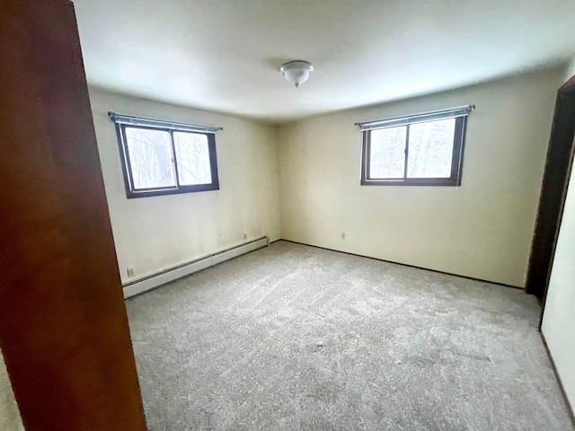 carpeted spare room featuring plenty of natural light and a baseboard heating unit